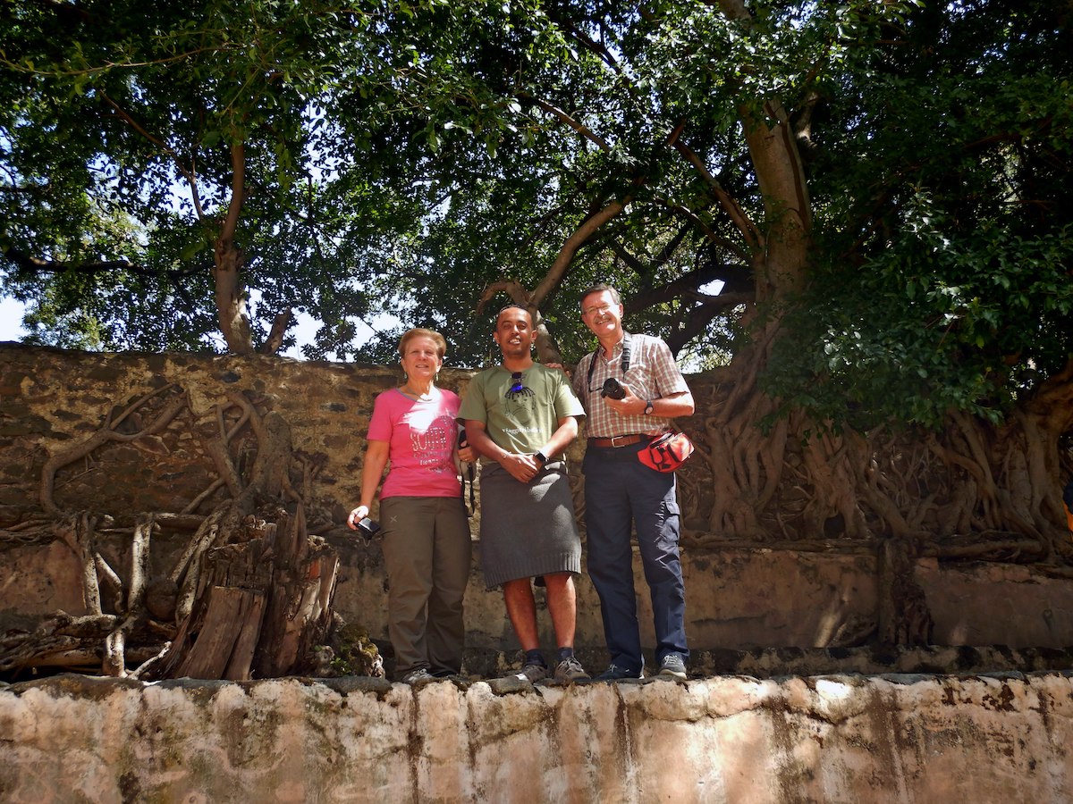 Due turisti italiani in posa con una guida locale all'ombra di un grande albero durante un viaggio in Etiopia