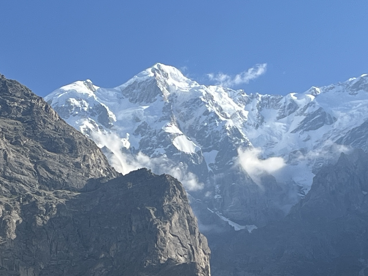 Vista ravvicinata di una maestosa montagna, con la cima completamente innevata e rocce scure in primo piano