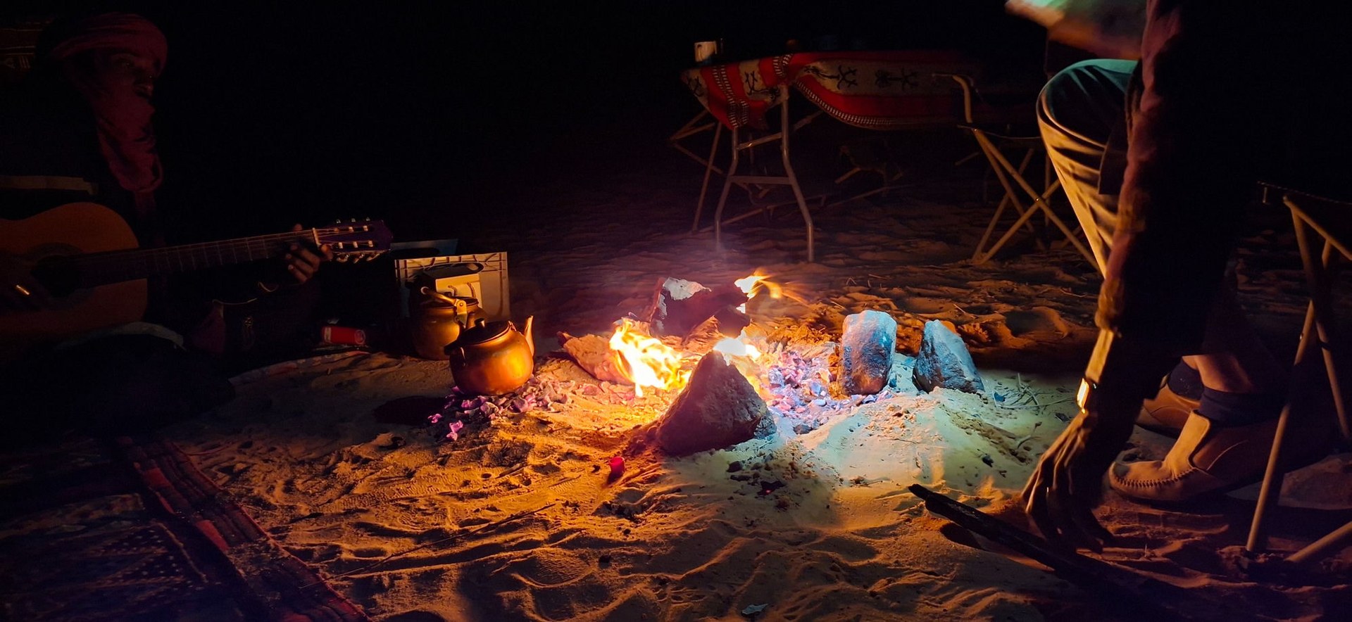 Falò notturno al campo con chitarra e teiera durante il tour nel deserto del Tassili, Algeria