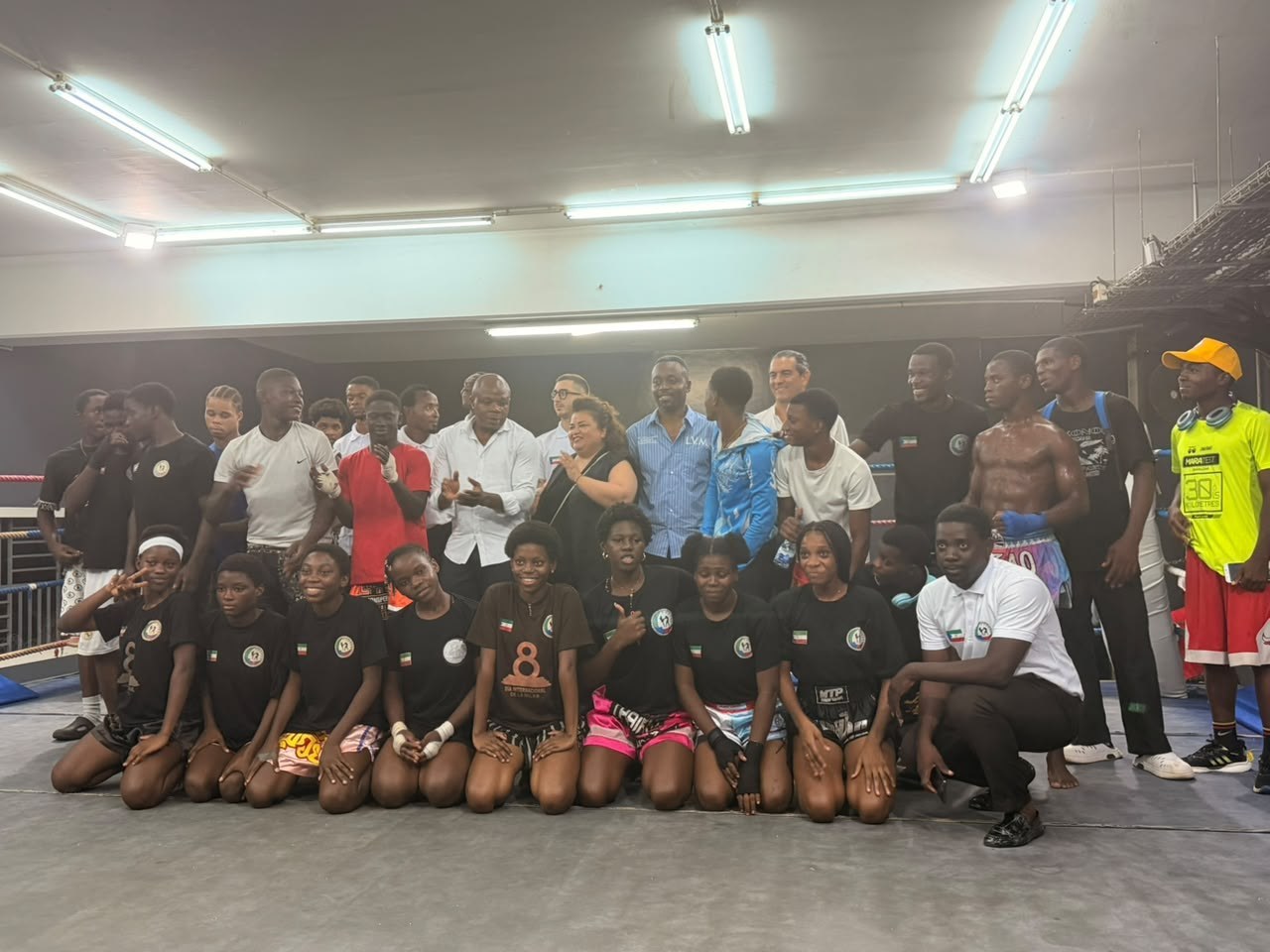Gruppo di atleti di kickboxing in posa con lo staff dopo l'incontro, alcuni inginocchiati in prima fila