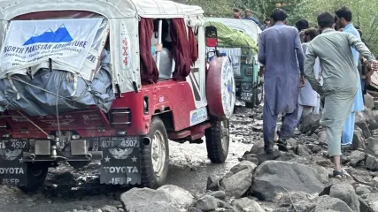 Jeep 4x4 rosse e verdi bloccate su una strada di montagna molto rocciosa in Pakistan; un gruppo di uomini cammina